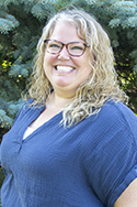 A portrait of Kellie Gilliland in front of a pine tree.